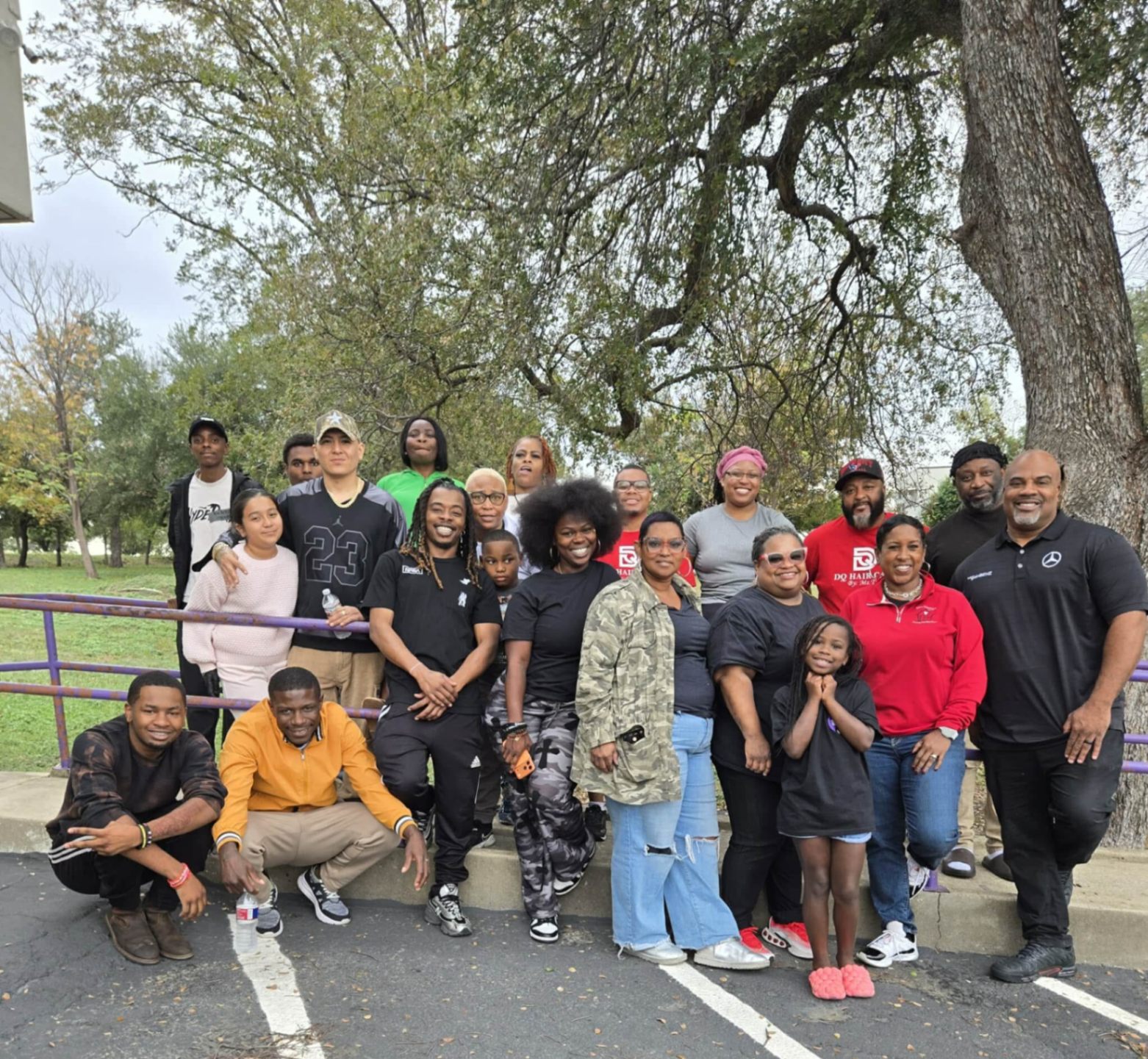 A large group of STEPS volunteers and community members of all ages posing together outdoors under a tree in Austin