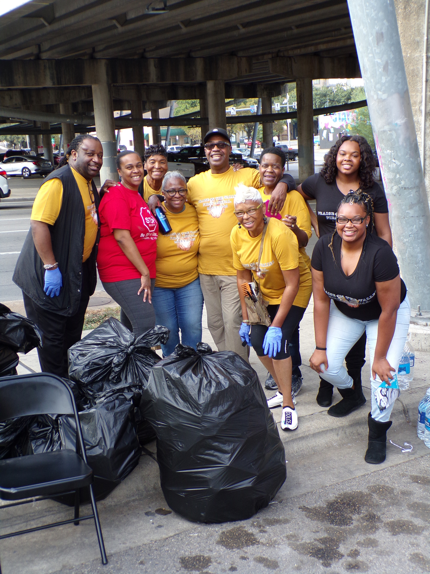 A group of STEPS volunteers and neighbors posing with bags of supplies and cases of water after a street distribution in Austin