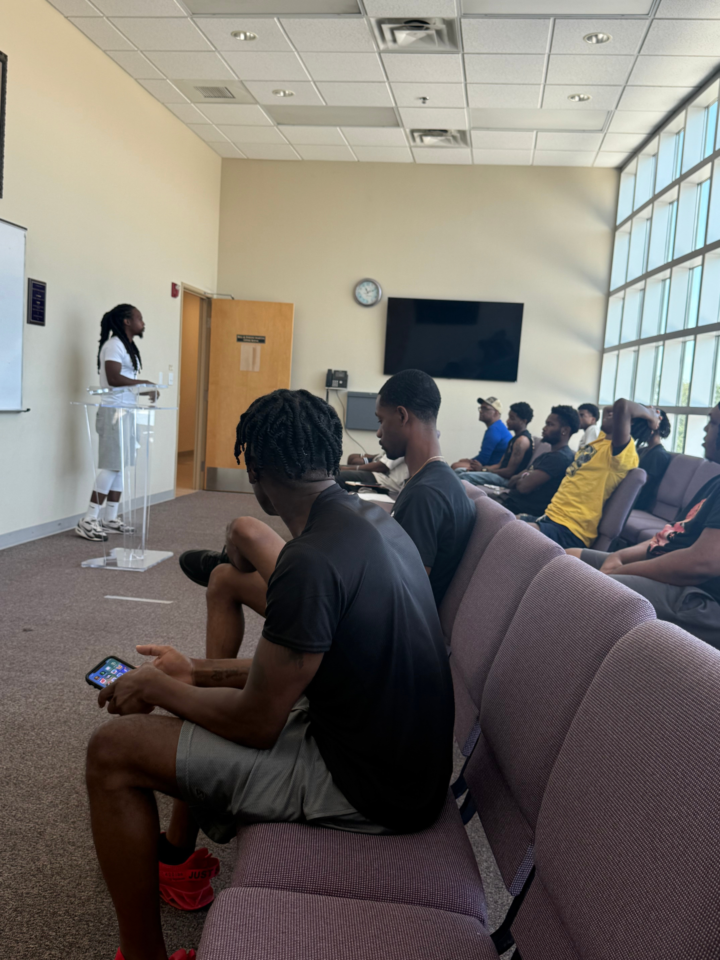 A STEPS mentor speaking to a room of young men seated in rows during a mentoring session in Austin